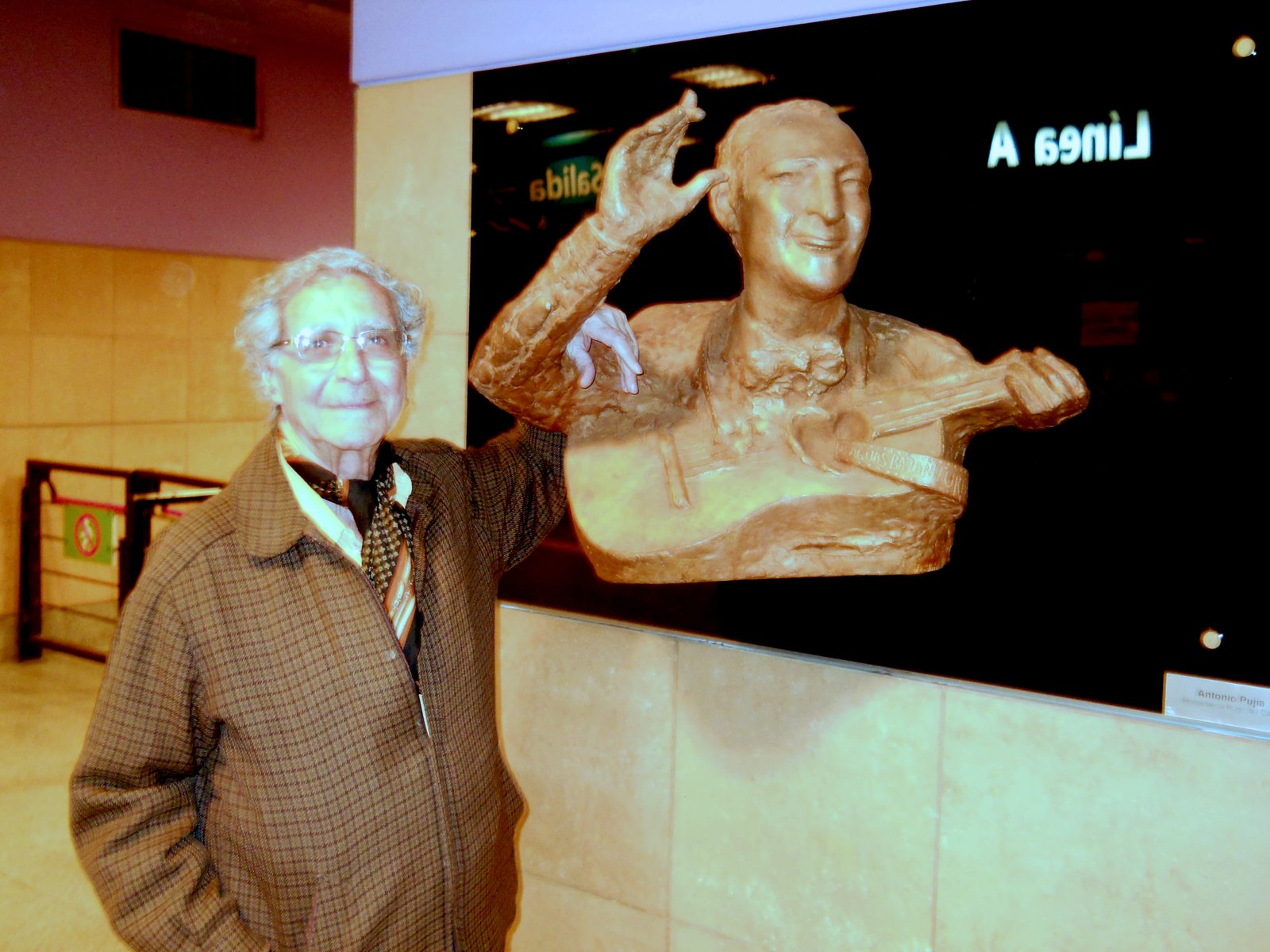 Antonio Pujía y la escultura que recuerda a Hugo del Carril, en la estación "San Pedrito".